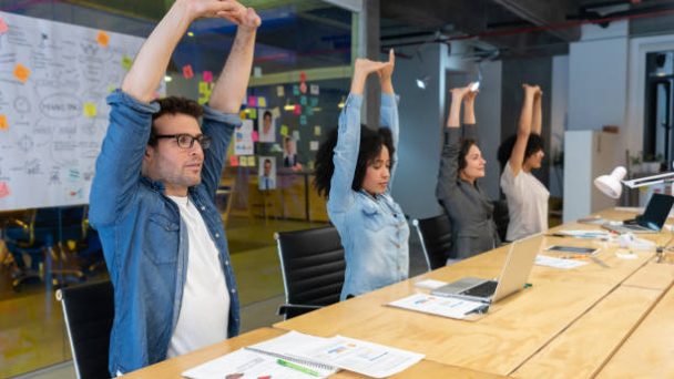 Group of Latin American Workers doing stretching exercises in a business meeting at the office - healthy lifestyle concepts